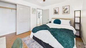 Ein Schlafzimmer mit einem Bett, einem Deckenventilator, einer Tür und einem Flur.