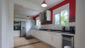 A kitchen with white cabinets, a black countertop, a coffee maker, and a dishwasher. - Villa Écume Verte - 2 bedrooms, terraces, quiet & close to Sainte-Anne beaches (Sainte-Anne)