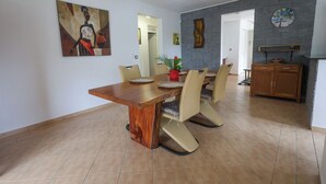 A dining area with a wooden table, beige chairs, and a potted plant. - Villa Écume Verte - 2 bedrooms, terraces, quiet & close to Sainte-Anne beaches (Sainte-Anne)