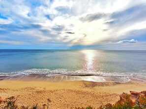 Una playa con agua cristalina, una orilla arenosa y un cielo parcialmente nublado.