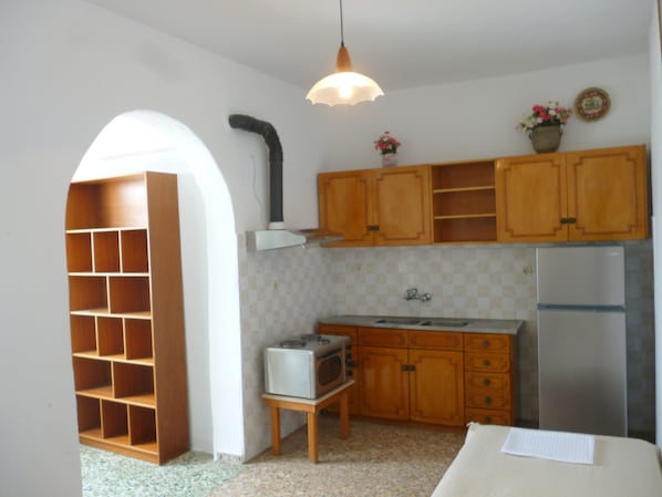 Una cocina compacta con armarios de madera, un microondas integrado y un refrigerador.