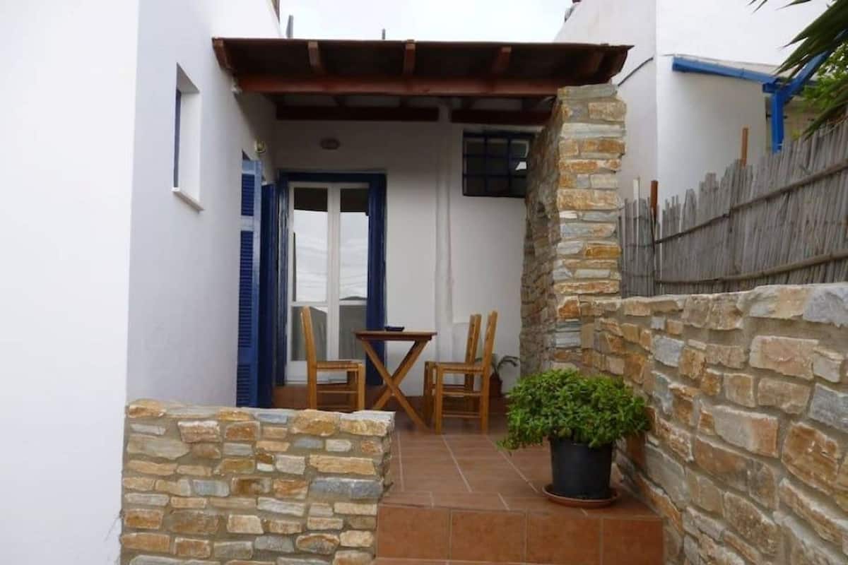 A small patio with a table and chairs, a potted plant, and a stone wall.