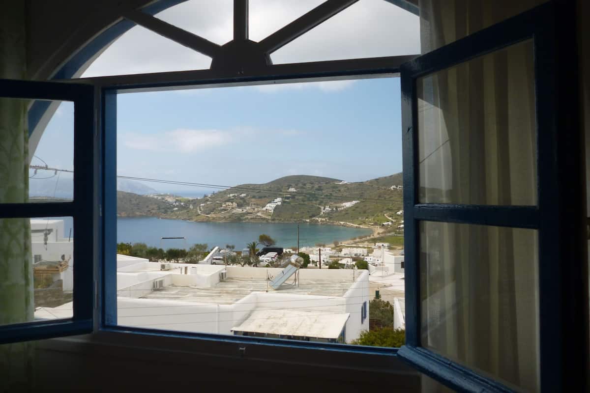 A view through a window with a curved top, overlooking a coastal area with buildings and a body of water.