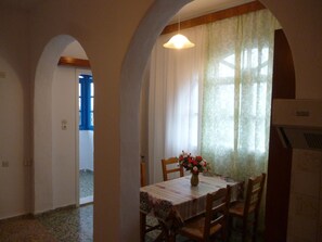 A dining area with a table set for four, a vase of flowers, and a window with curtains.
