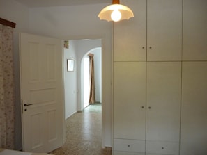 Un pasillo con una puerta blanca, un armario y una lámpara.
