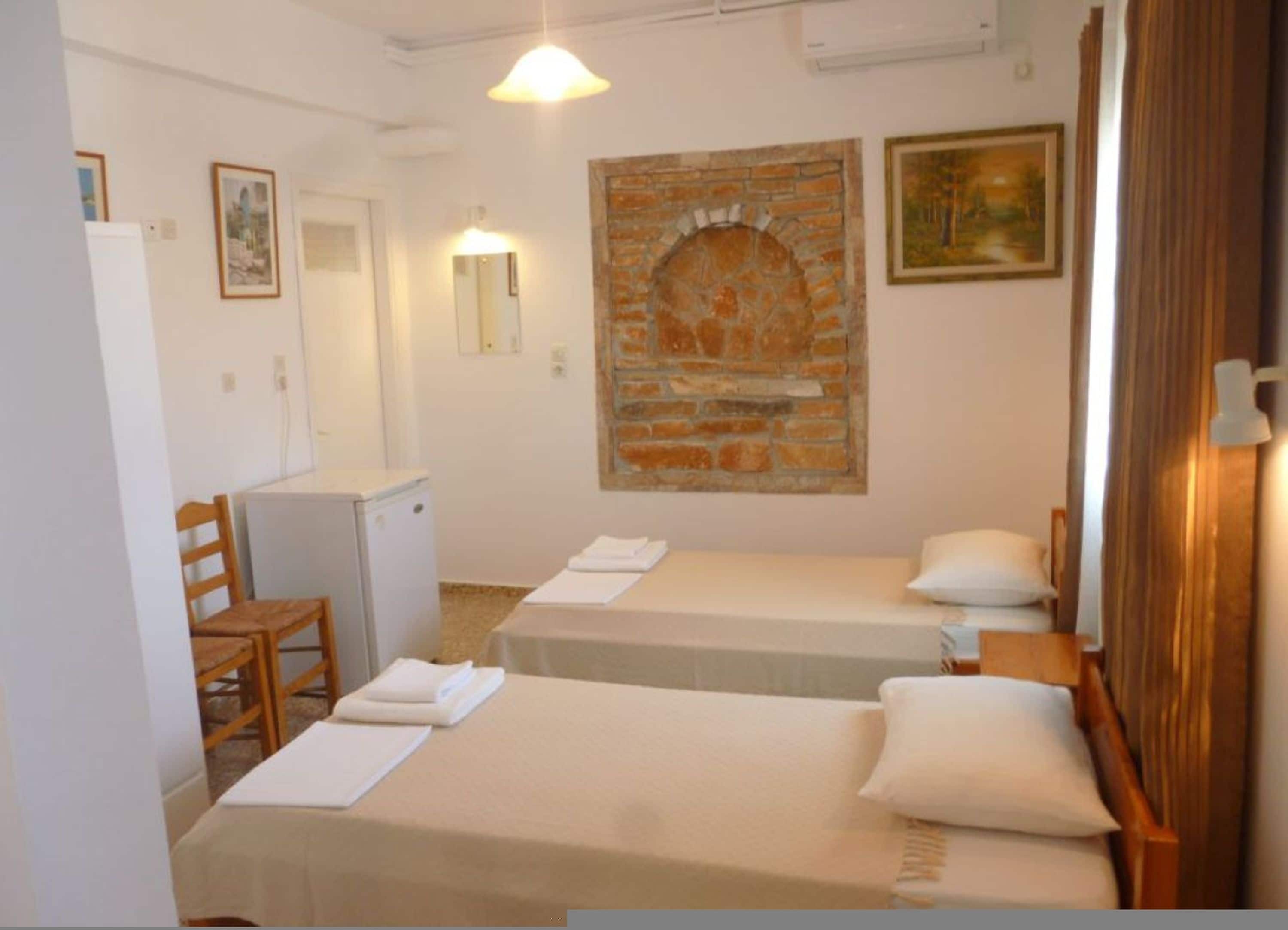 Habitació d'hotel amb dos llits, un taulell petit, una cadira, un mirall i una decoració de paret de maó.