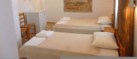 Habitació d'hotel amb dos llits, un taulell petit, una cadira, un mirall i una decoració de paret de maó.