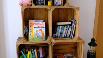 Ein Bücherregal aus Holz mit Büchern, einer Puppe, einer Uhr und einer Laterne.