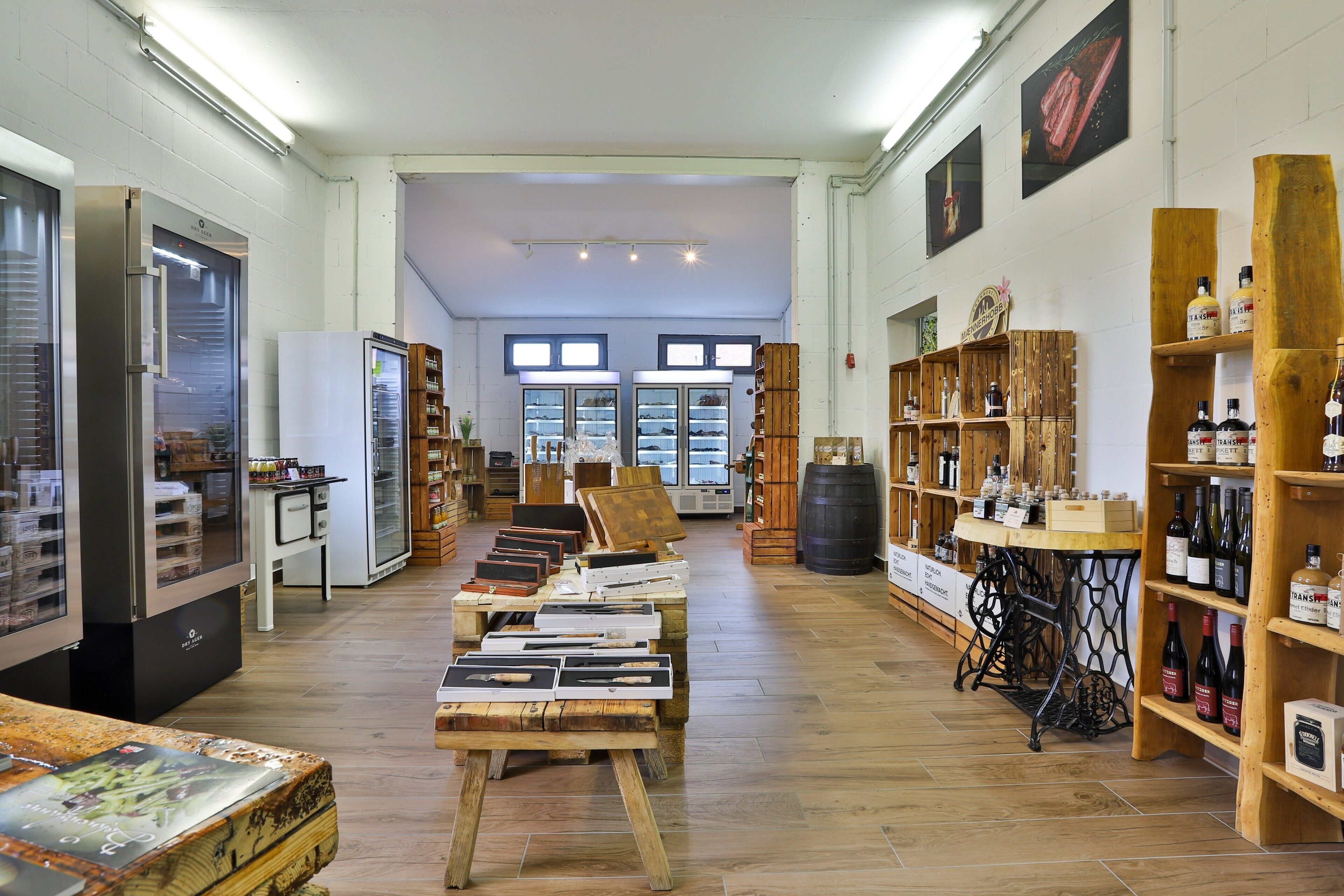 A spacious interior with wooden flooring, a central display table, and shelves with bottles.