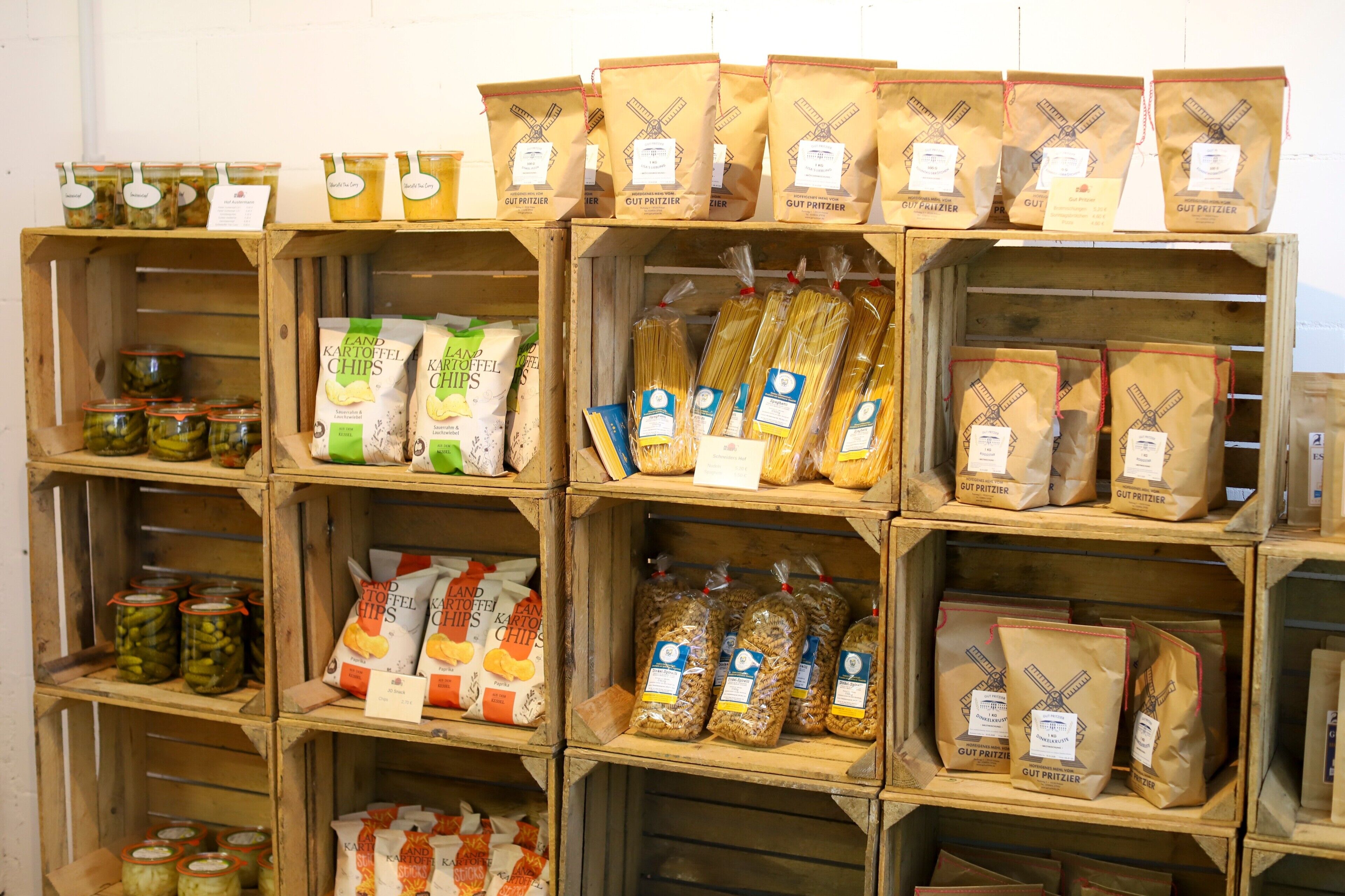 Wooden crates stacked with various food items like chips, pasta, and canned goods.
