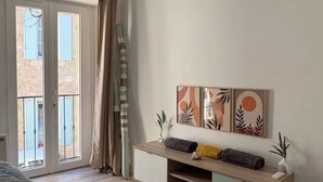 Un dormitorio con cama, mesita de noche, cómoda, ventilador de techo y puerta corrediza de vidrio que da a un espacio exterior.