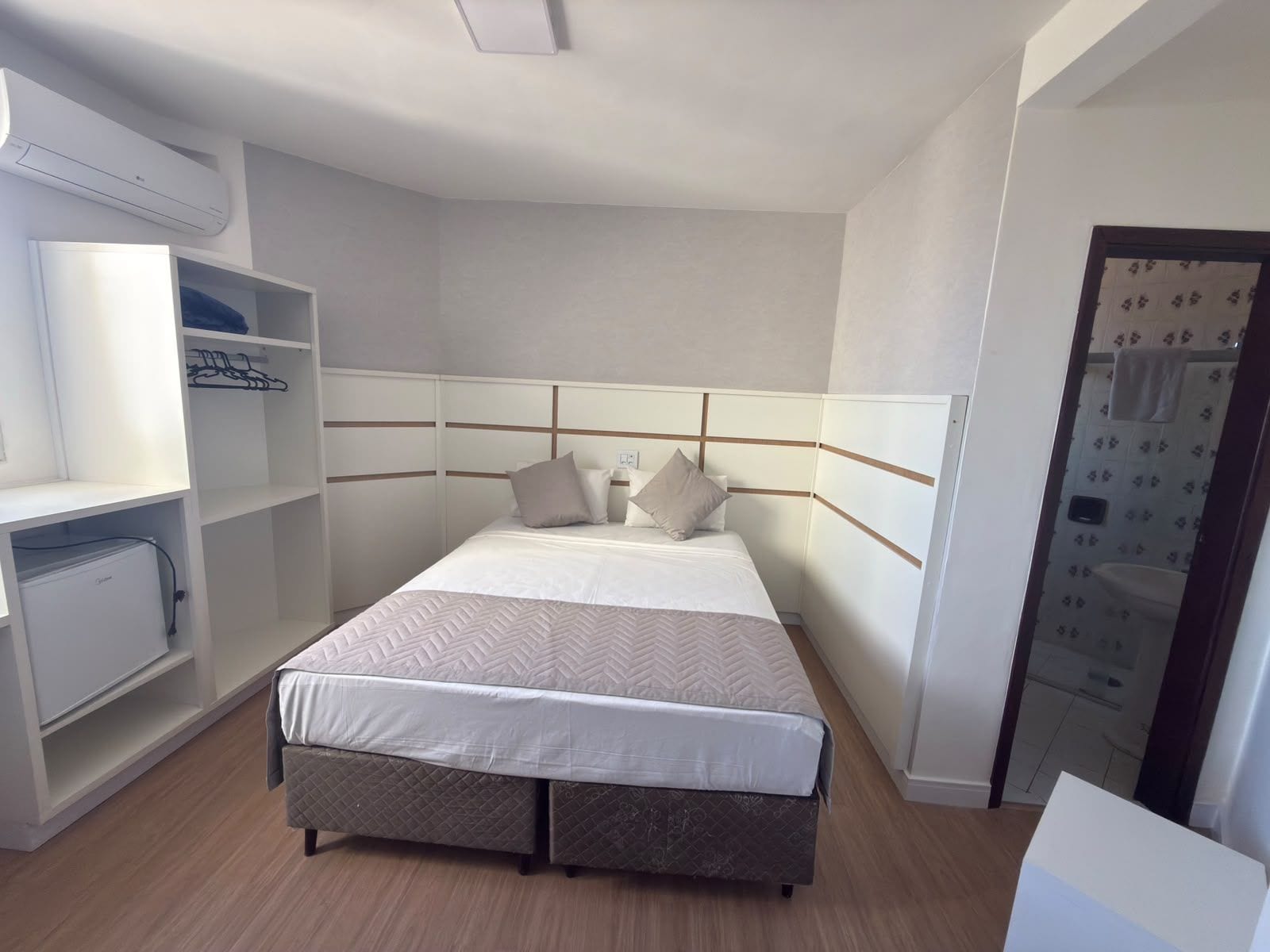 Habitación de hotel con cama, armario empotrado y escritorio pequeño.