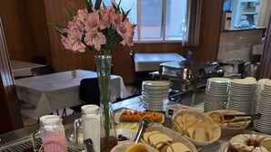 Een buffet met diverse gerechten, een bloevas en een zicht op de keuken op de achtergrond.