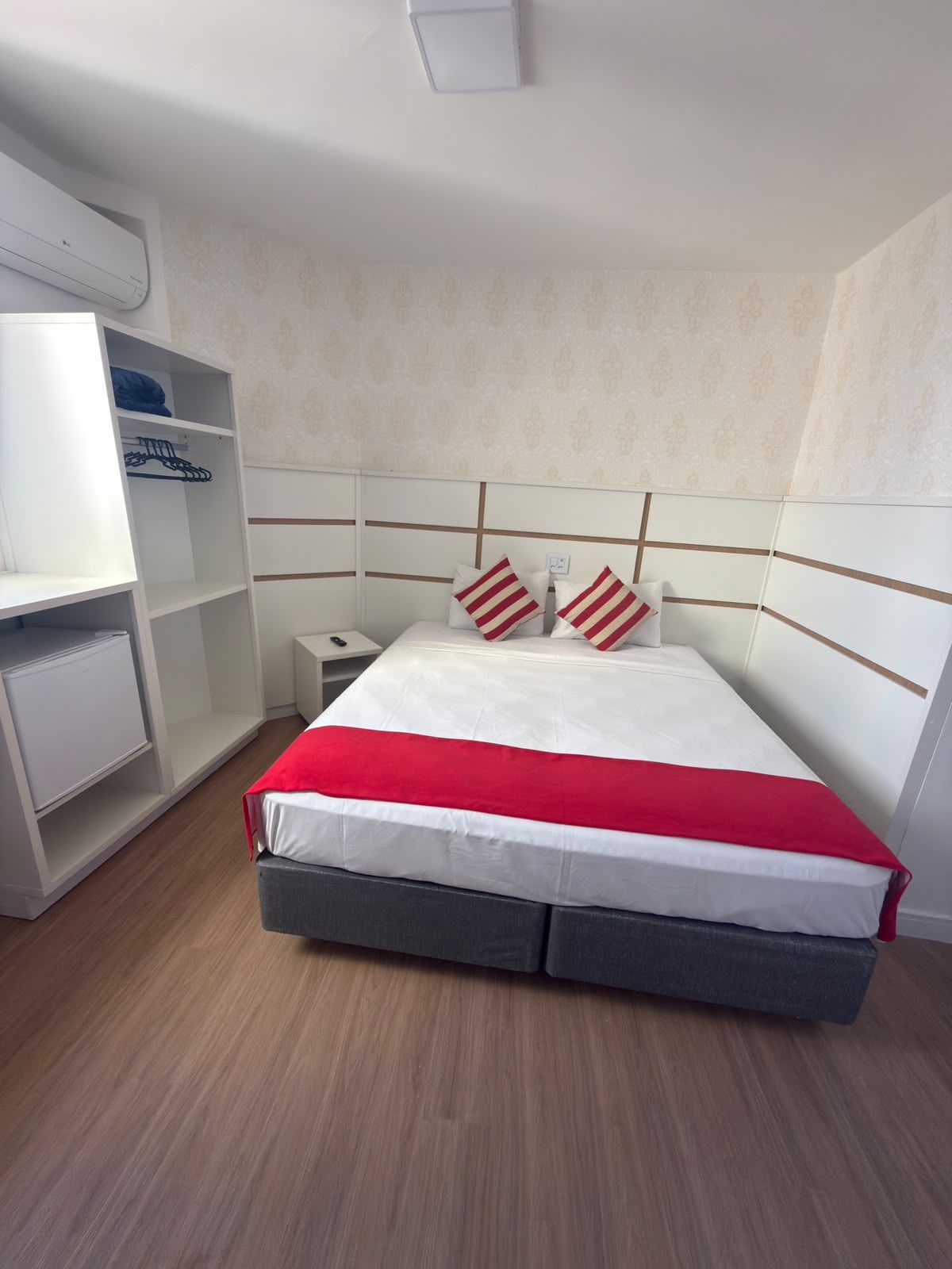 Een slaapkamer met een bed, nachtkastje, kledingkast en een ingebouwde airconditioning.