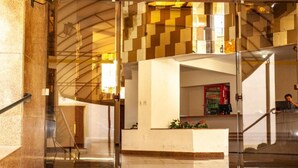 Een hotel lobby met een receptiebalie, een trap en een Coca-Cola koelkast.