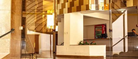 Un vestíbulo de hotel con una recepción, una escalera y un refrigerador de Coca-Cola.