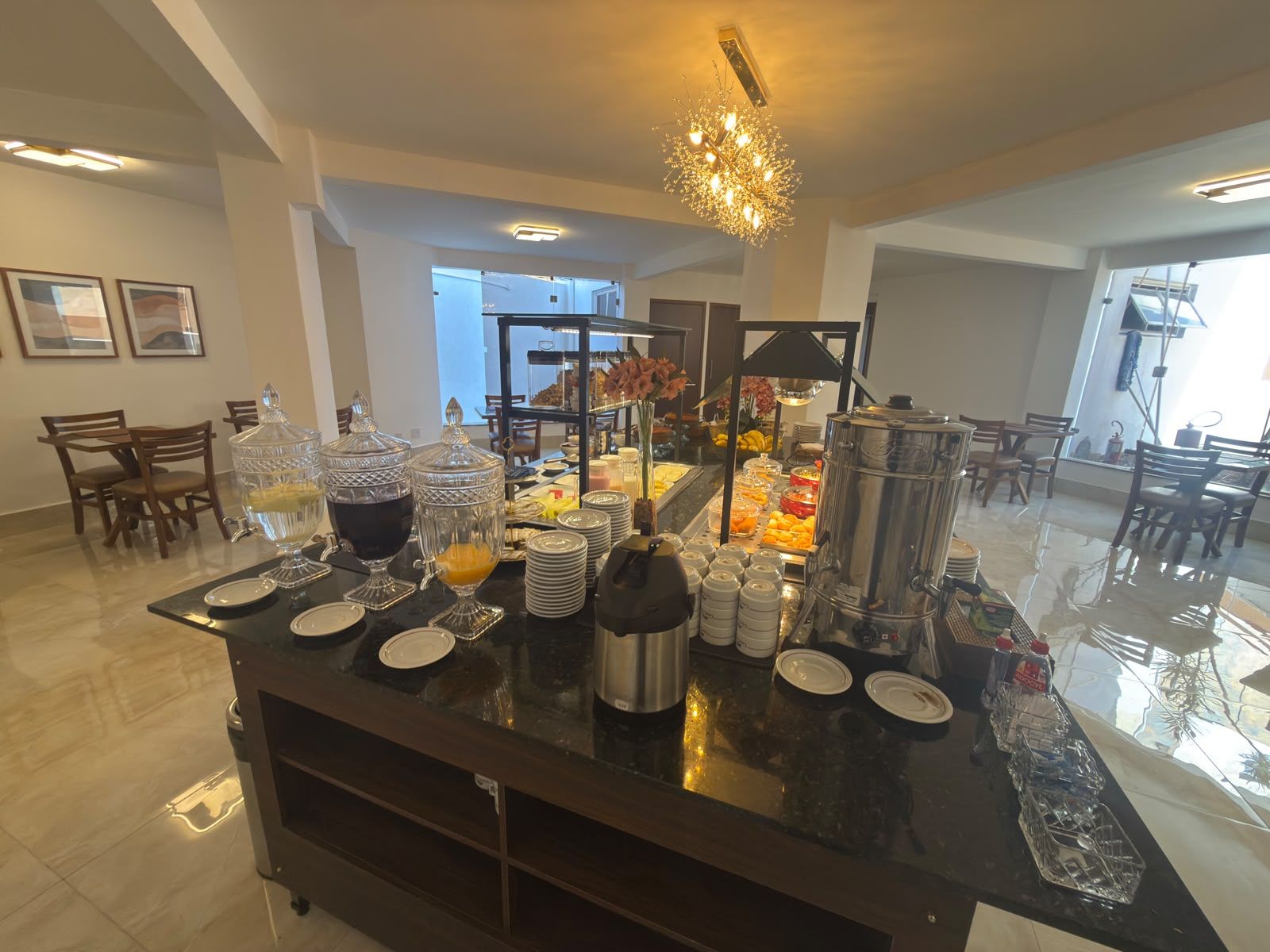 A buffet setup with various food items, a coffee station, and a decorative chandelier.