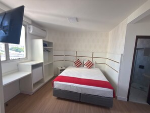 A bedroom with a bed, a desk, a chair, a TV, and a window. - GRANCENTRO HOTEL (Mogi-Guacu)