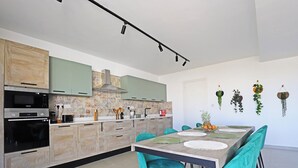 Una cucina moderna con zona pranzo, caratterizzata da una grande isola, elettrodomestici integrati e diverse decorazioni a parete.