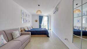 Una camera da letto con un letto, una poltrona, uno specchio e opere d'arte appese al muro.