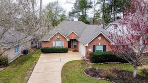 A two-story house with a brick exterior, a front porch, and a driveway. - Beautiful 3-bedroom house in The Woodlands (Spring)