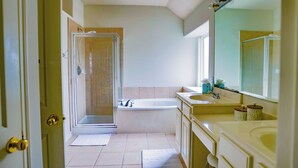 Een badkamer met douche, bad, wastafel en spiegel.