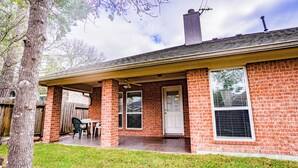 Een bakstenen huis met een overdekte patio, een deur en een raam.