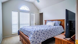 Een slaapkamer met een groot bed, een televisie en een raam met zonwering.