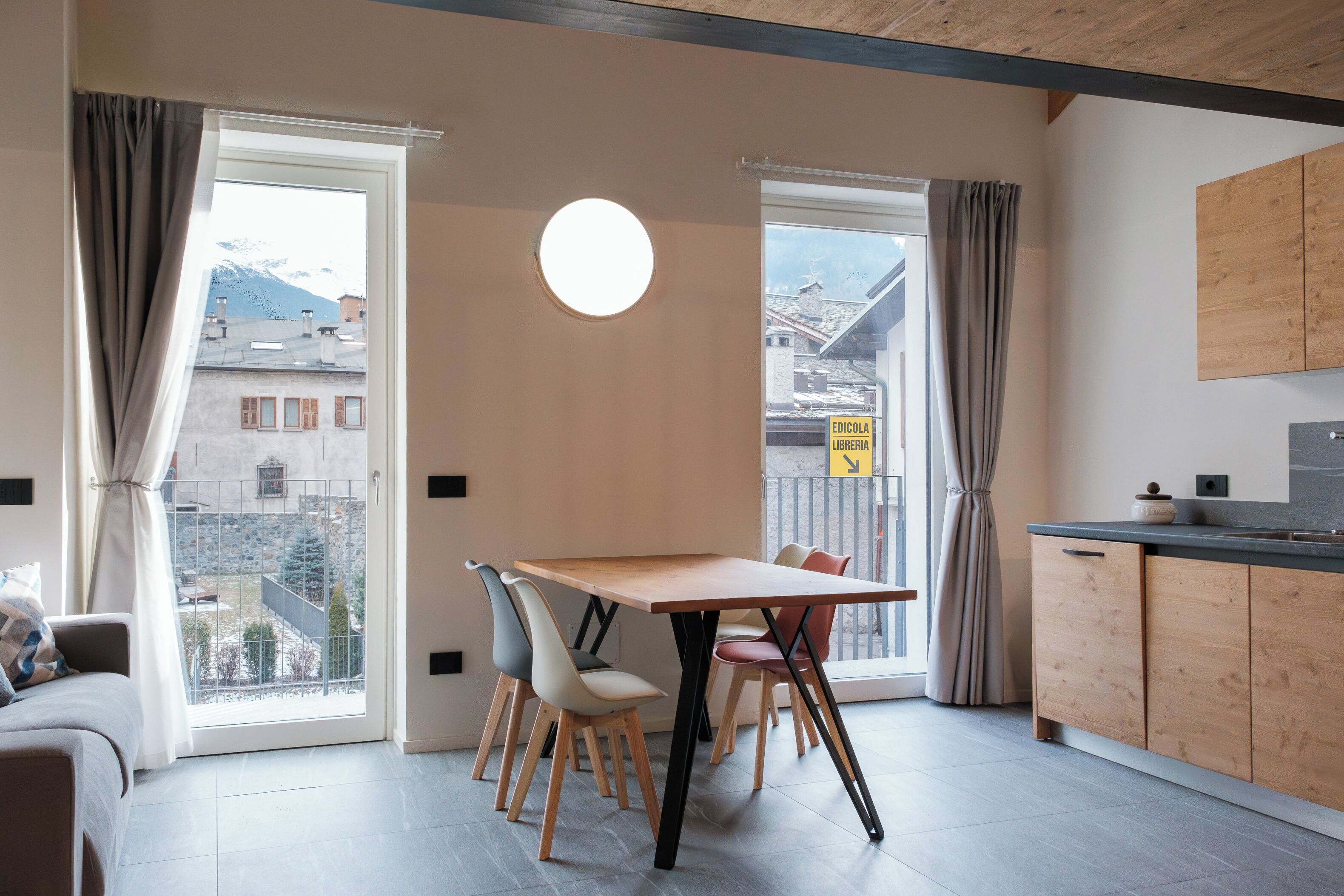 Eine moderne Wohnung mit Essbereich, Küche und großen Fenstern mit Vorhängen.