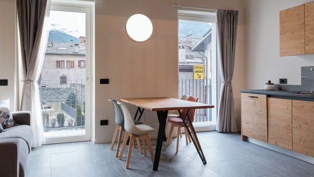 A modern apartment with a dining area, kitchen, and large windows with curtains. - Apartment 3 Casa Bepa • In the heart of Bormio, ideal for skiing and relaxation (Bormio)