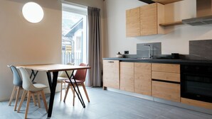 A modern kitchen with wooden cabinets, a black countertop, and a built-in oven. - Apartment 3 Casa Bepa • In the heart of Bormio, ideal for skiing and relaxation (Bormio)