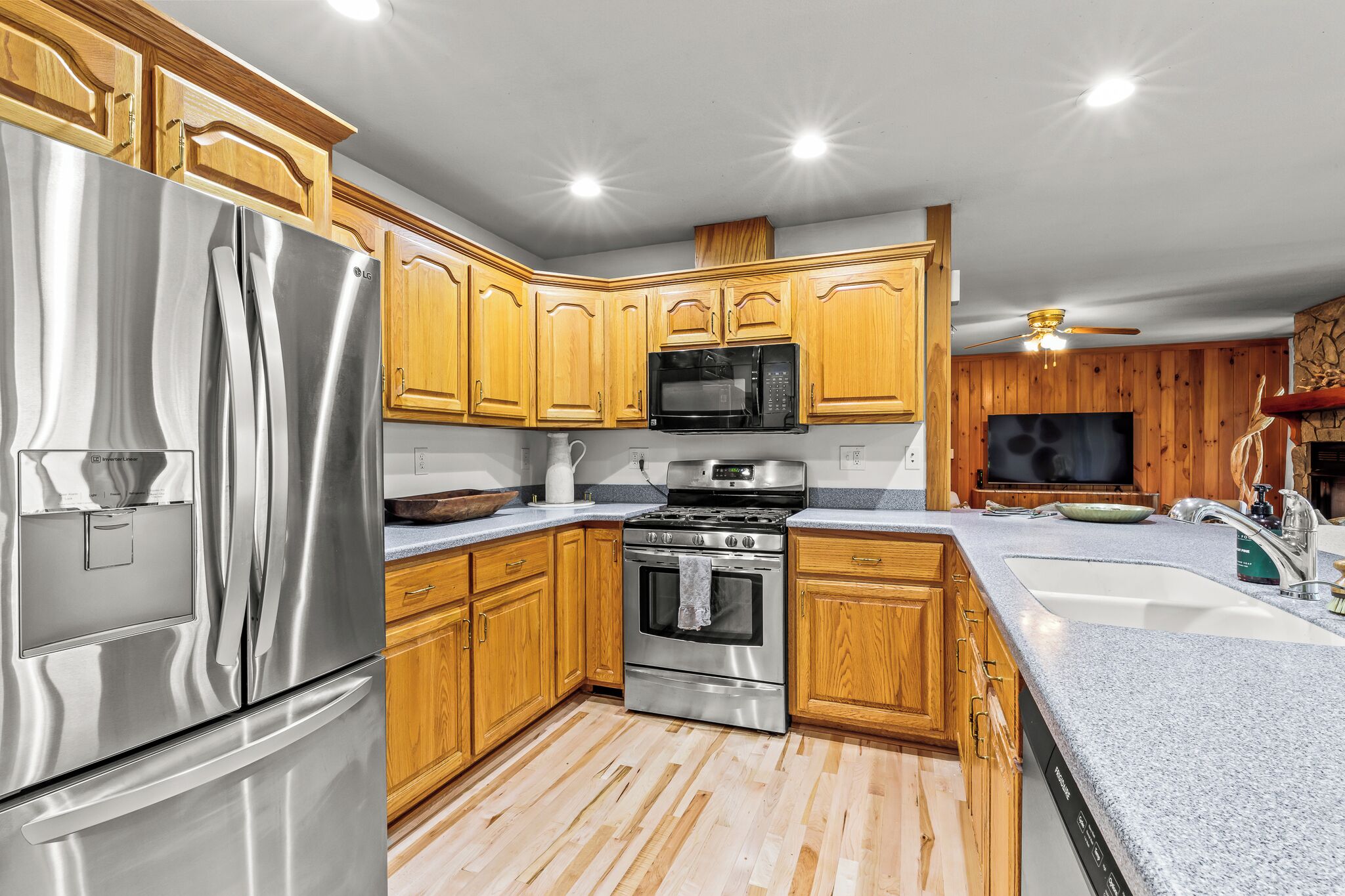 Una cocina con gabinetes de madera, electrodomésticos de acero inoxidable y encimera de granito.
