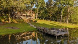 A lakeside property with a wooden dock, a staircase leading to a building, and a reflection in the water. - Serene Lakefront Retreat w/ Private Hot Tub in Gated Community. (Blue Ridge)