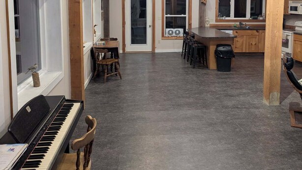 Tilava huone, jossa on piano, ruokapöytä ja keittiötila.