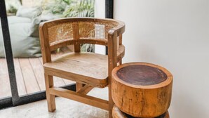 A wooden chair and a multi-tiered wooden stool in a room with a concrete floor and a view of greenery outside. - Welcome to your private oasis in the heart of Tulum! (Tulum)