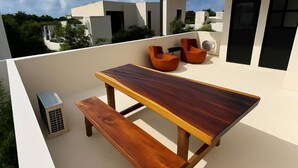 A rooftop terrace with a wooden table and benches, an air conditioning unit, and orange chairs. - Welcome to your private oasis in the heart of Tulum! (Tulum)