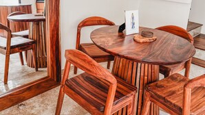 A dining area with a round wooden table and chairs, a mirror reflecting the space, and a white staircase in the background. - Welcome to your private oasis in the heart of Tulum! (Tulum)