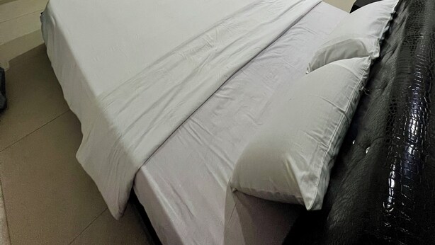 Una camera da letto con un letto, una TV a parete, un tavolino e un armadio.