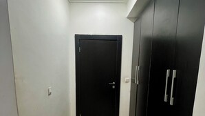 Un corridoio con una porta nera, una luce a soffitto e un pavimento piastrellato.