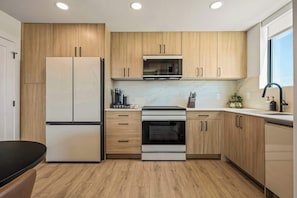 Une cuisine moderne avec des meubles en bois, un four encastré et un four à micro-ondes.