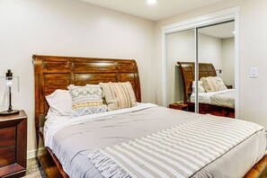 Ein Schlafzimmer mit einem Holzkopfteil, einem großen Spiegel und einem Bett mit gestreifter Bettwäsche.