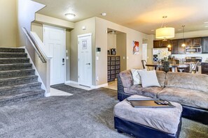 Ein Wohnzimmer mit Sofa, Hocker und einer Treppe, die in einen anderen Raum führt.