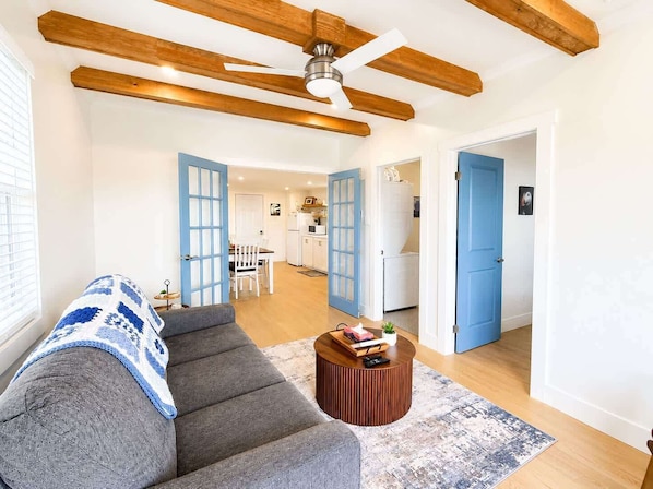 Un salon avec un canapé gris, une table basse en bois et un ventilateur de plafond.
