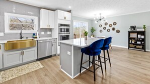 Una cucina moderna con isola centrale, sgabelli da bar e zona pranzo.