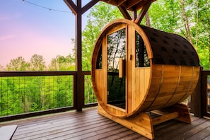 A wooden barrel-shaped structure with a door and windows, situated on a wooden deck with a view of a forest. - 5*Retreat w/Indoor Pool~FirePit~Arcade~Playground (Sevierville)
