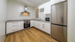 A modern kitchen with white cabinets, a stainless steel refrigerator, a microwave, and a built-in oven. - Apartment inside the Wall of Lugo, Rúa Nova (Lugo)