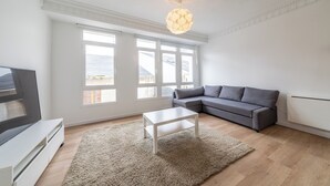 A modern living room with a grey sofa, a white coffee table, and a large window with a view of the sea. - Apartment inside the Wall of Lugo, Rúa Nova (Lugo)