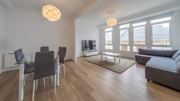 A modern living room with a glass dining table, grey chairs, a grey sofa, and a TV on a white stand. - Apartment inside the Wall of Lugo, Rúa Nova (Lugo)