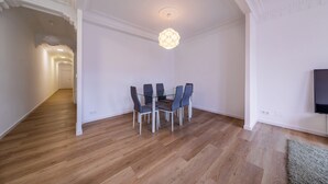 A dining area with a glass table and chairs, a ceiling light fixture, and a TV on the wall. - Apartment inside the Wall of Lugo, Rúa Nova (Lugo)