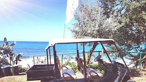 A golf cart parked near a beach with a clear view of the ocean.